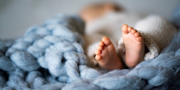 Foot of newborn baby on warm blanket